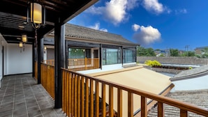 A modern building with a traditional tiled roof, large windows, and a wooden balcony railing. - Silk Road-Fu Tea Town Boutique Homestay (Xianyang)