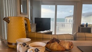 A dining area with a table set for breakfast, including a coffee pot, two cups, and croissants. - Waterside, Paignton - Holiday Accommodation 19143 (Paignton)