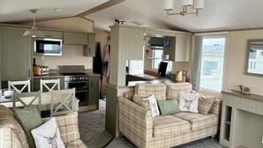 A compact living space with a kitchenette, a sofa, and a dining area. - Waterside, Paignton - Holiday Accommodation 19143 (Paignton)