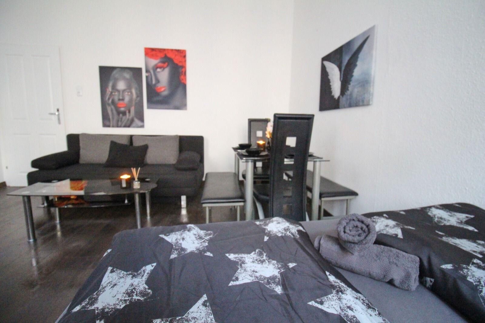 Un dormitorio moderno con una cama grande, un sofá, un escritorio y dos obras de arte en la pared.