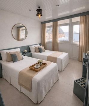 A hotel room with two beds, a large window with curtains, a round mirror, and a small table with a tray. - Modern Apartment in Prime Location (Alanya)