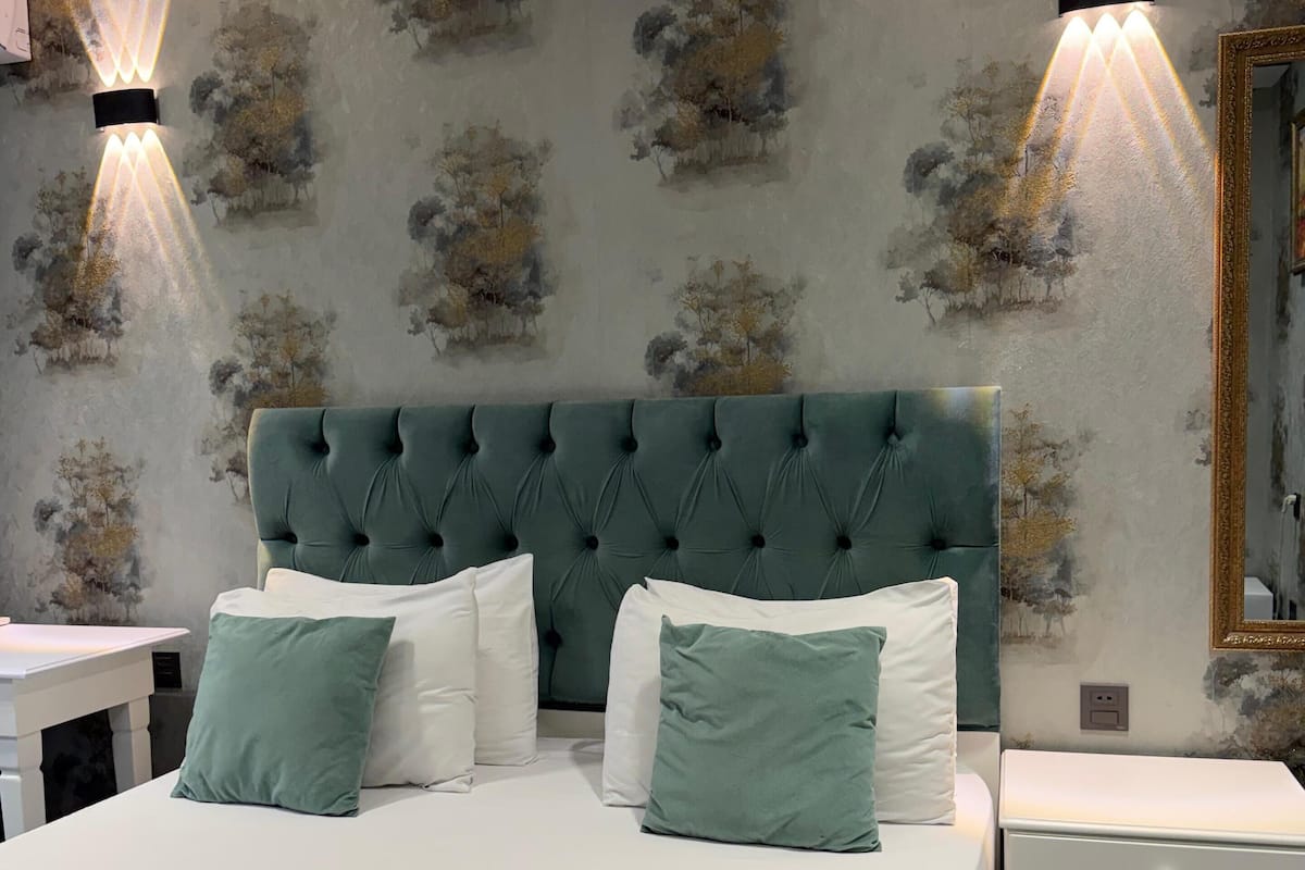 Une chambre à coucher avec un grand lit, deux tables de chevet, une commode et un miroir fixé au mur.