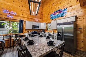 A kitchen with wooden walls, a granite countertop, and stainless steel appliances. - Blue Suede Views: Indoor Pool & Mtn Views (Pigeon Forge)