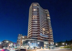 A modern hotel with a curved facade, multiple balconies, and a prominent entrance with glass doors.