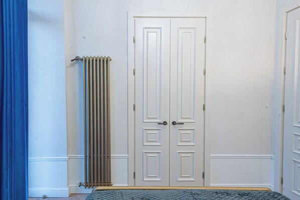 A room with a double door, a radiator, and a blue curtain.
