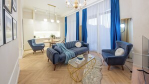 A modern living room with a sofa, armchairs, a coffee table, and a chandelier. - HB apartments University Agro (Tbilisi)