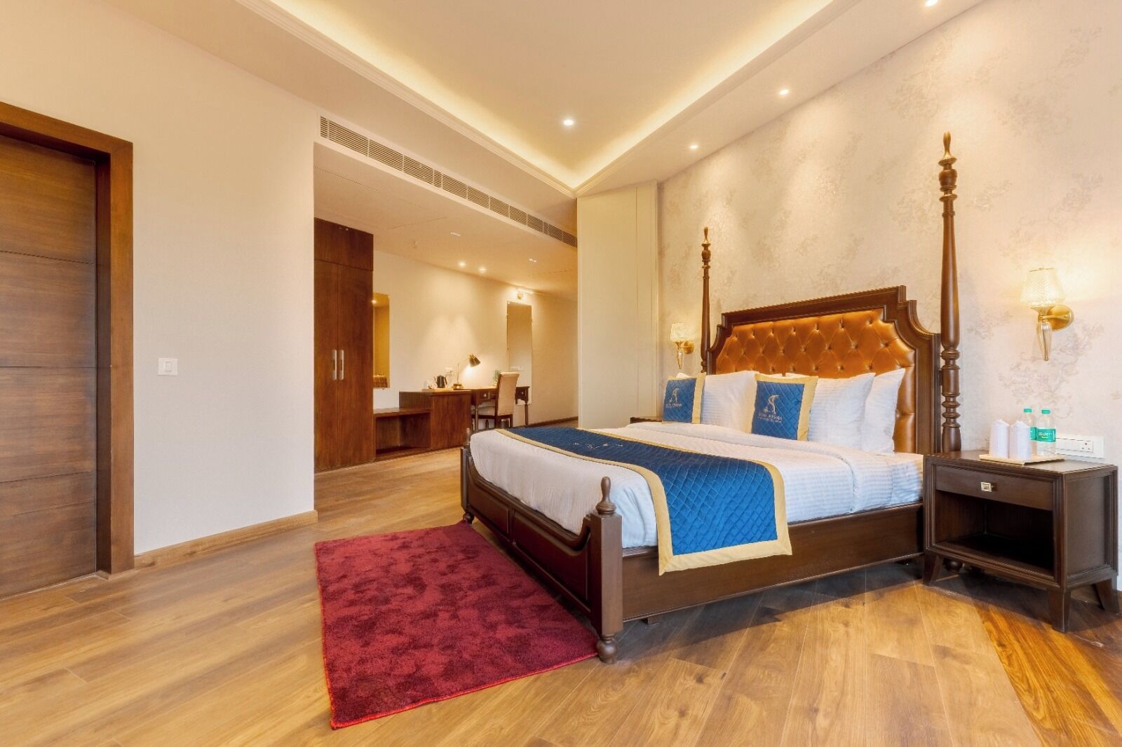 A spacious bedroom with a large bed, a wooden nightstand, and a red rug.