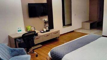 Una habitación de hotel con cama, escritorio, silla, televisor y ventana.