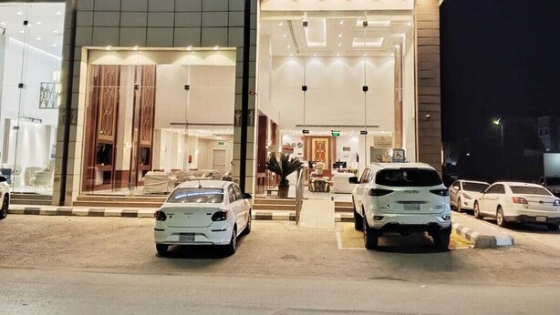 A building with a sign for Alfursan Serviced apartments. There are cars parked in front, and the entrance has a glass door. - alfursan servived appartment (Al Kharj)