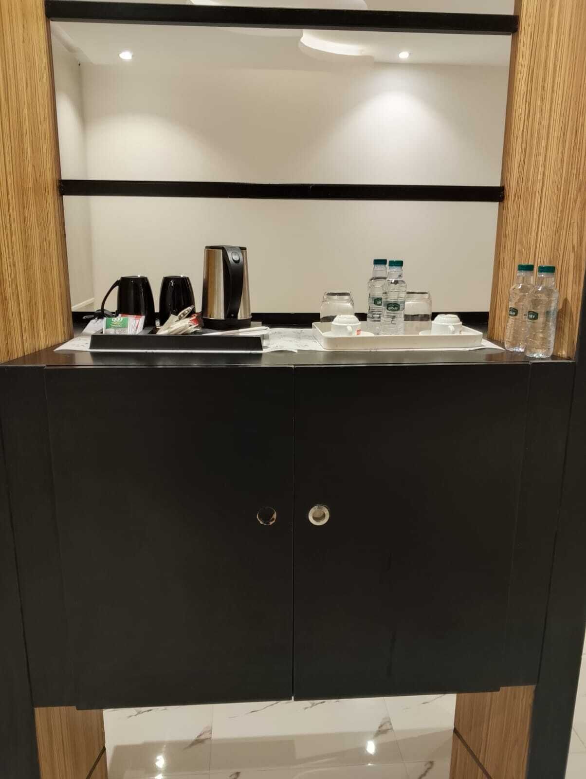Un baño moderno con tocador negro, cafetera y agua embotellada.