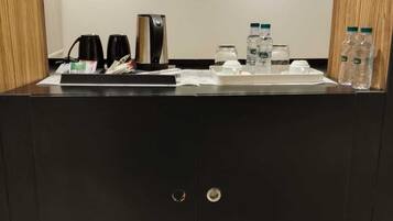 Un baño moderno con tocador negro, cafetera y agua embotellada.