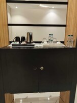 Un baño moderno con tocador negro, cafetera y agua embotellada.