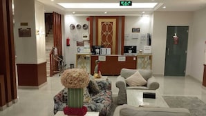 A hotel lobby with a reception desk, seating area, and a staircase leading to an upper floor. - alfursan servived appartment (Al Kharj)