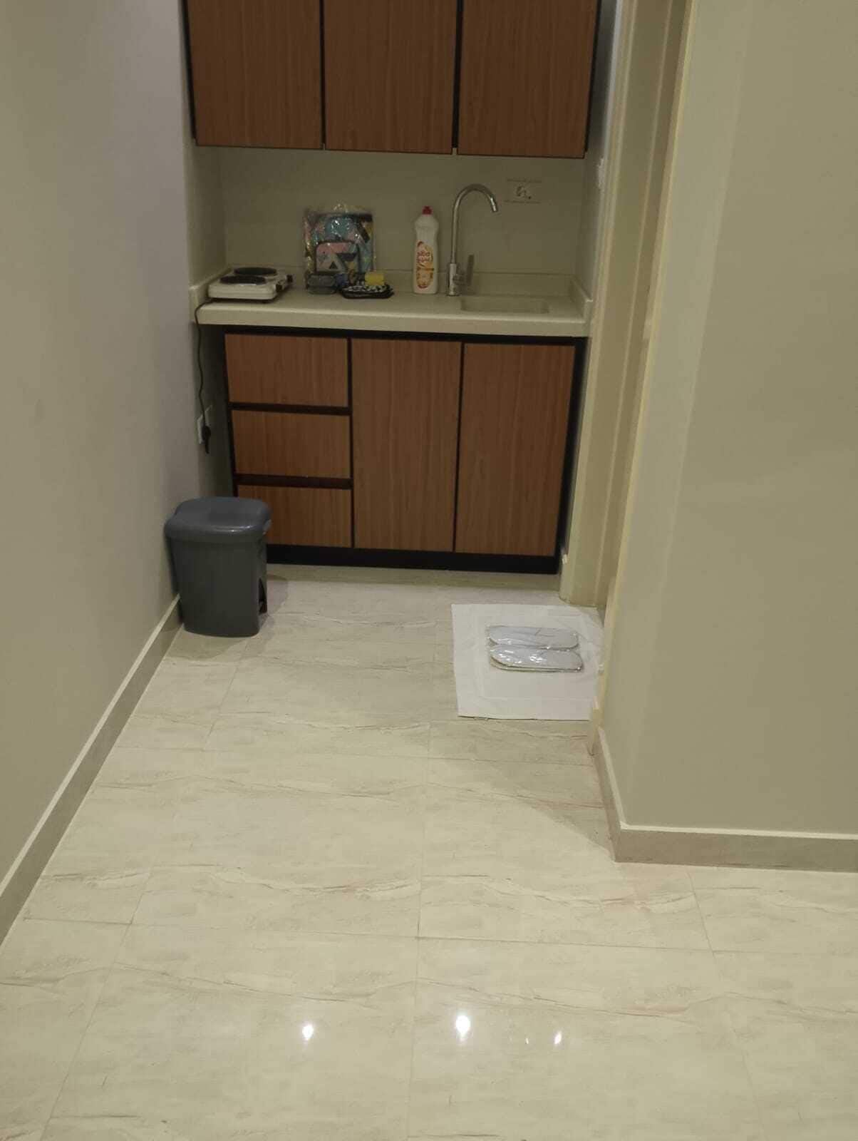 A small kitchen with wooden cabinets, a sink, and a trash bin.