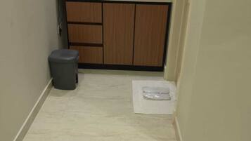 A small kitchen with wooden cabinets, a sink, and a trash bin.