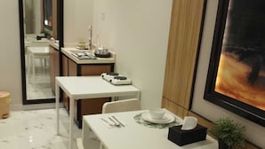 A dining area with a white table set for four, including plates, bowls, and cutlery. A small plant and a framed picture are on the table. - alfursan servived appartment (Al Kharj)