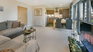 Un appartement moderne comprenant un salon, un coin repas, une cuisine et une grande fenêtre offrant une vue dégagée.