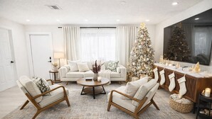 Un salón moderno con un sofá blanco, dos sillones, una mesa de centro y un árbol de Navidad.
