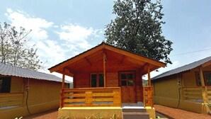 Una cabaña de madera con porche, rodeada de un jardín ajardinado.