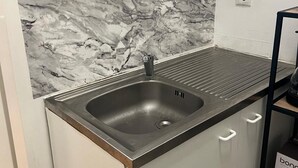A kitchen with a marble backsplash, a stainless steel sink, and a black countertop. - Modern 1BR City Apt for 5 Great Location (Vienna)