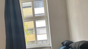 A room with a bed, a window with blinds, a radiator, and a curtain. - Modern 1BR City Apt for 5 Great Location (Vienna)