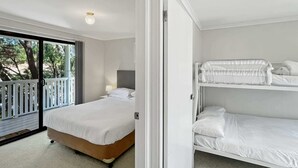 Quarto com uma cama de solteiro, uma cama beliche e uma varanda com guarda-corpo.