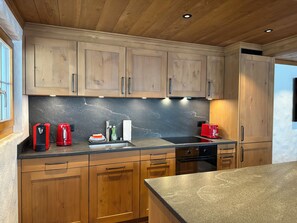A modern kitchen with wooden cabinets, a granite countertop, and stainless steel appliances. - Serene and relaxing 2 bedroom apartment with panoramic views (Saanen)