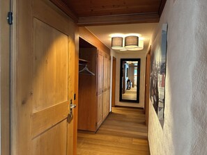 A hallway with wooden doors and a mirror reflecting the room. - Serene and relaxing 2 bedroom apartment with panoramic views (Saanen)