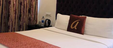 A hotel room with a bed, a headboard, an air conditioning unit, a nightstand, and a curtain.