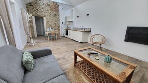 Een moderne woonkamer met een grijze bank, een houten salontafel en een stenen muur.