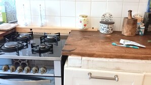 Eine Küche mit einem Gasherd, einer Holzausziehtafel und verschiedenen Küchenutensilien.