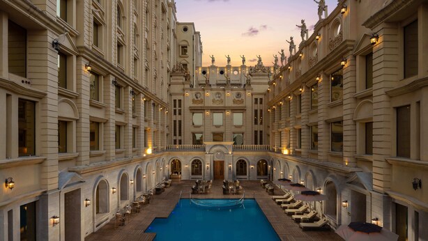 Un espace piscine agrémenté de chaises longues et de parasols, le tout entouré d’une architecture classique.