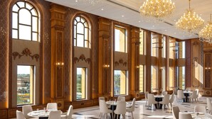 A spacious dining area with multiple tables and chairs, large windows, and ornate chandeliers. - Blueworld Castles (Bilhaur)
