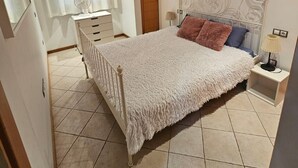 Une chambre à coucher avec un lit, une table de chevet, une commode et un miroir.