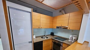 Une cuisine compacte avec des meubles en bois, un évier en acier inoxydable, une cuisinière et une machine à café.