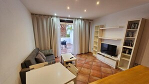 Un salon avec un canapé, un téléviseur, une bibliothèque et une table à manger.