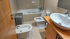 Une salle de bain moderne équipée d’une baignoire, de toilettes, d’un bidet et d’un lavabo.