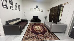 Una sala de estar con un sofá, un televisor, una alfombra y cuadros en la pared.