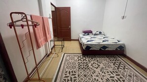 Una habitación pequeña y limpia con una cama, un tapete estampado y un tendedero con una toalla.