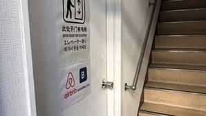 Eine Tür mit einem Aufzugsschild und dem Airbnb-Logo.