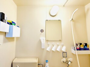 Une salle de bain équipée de toilettes, d’un lavabo, d’un miroir, d’un distributeur de serviettes et d’une douche.
