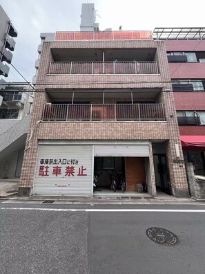Un immeuble à plusieurs étages avec une porte de garage fermée et une enseigne en japonais.