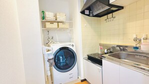 Ein kleiner Waschraum mit einer Waschmaschine mit Frontlader, einem Waschbecken und einer kleinen Ablage mit gefalteten Handtüchern.