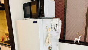 Eine kompakte Küche mit einem weißen Kühlschrank, einer Mikrowelle und einem kleinen Schrank.