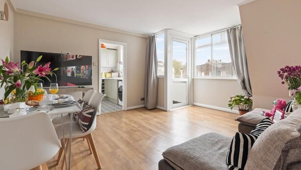 Ein modernes Wohnzimmer mit Essbereich, Fernseher und Blick auf die Stadt.