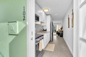 A modern kitchen with white cabinets, a stainless steel oven, and a built-in microwave. - Sandy Toes Retreat (Panama City Beach)
