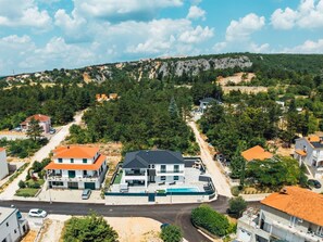 A residential area with modern houses, a swimming pool, and a road leading to a hilly landscape. - Villa Budimir by Interhome (Imotski)