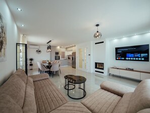 A modern living room with a sofa, a coffee table, and a dining area with chairs. - Villa Budimir by Interhome (Imotski)