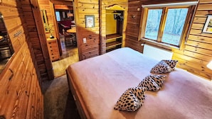 Ein Zimmer in einer Holzhütte mit Bett, Fenster und einer kleinen Essecke.
