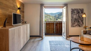 Une chambre moderne avec un mur en bois, un téléviseur à écran plat, un tableau et une vue sur un paysage montagneux.